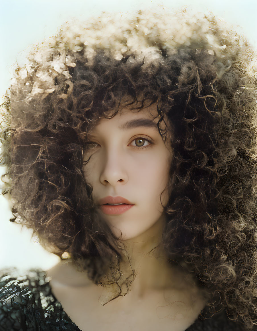 Woman with Voluminous Curly Hair in Soft Light and Dark Textured Top