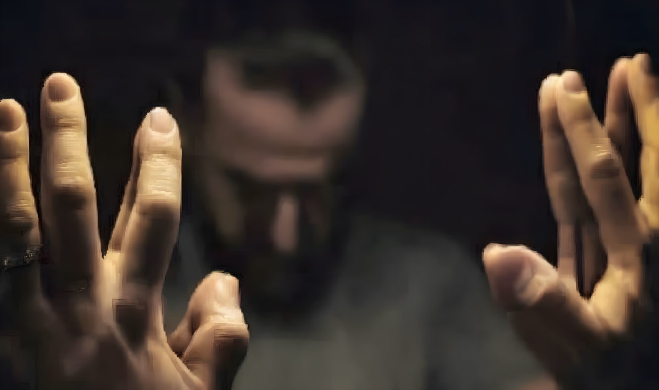 Person's Outstretched Hands with Blurred Face in Dimly Lit Background