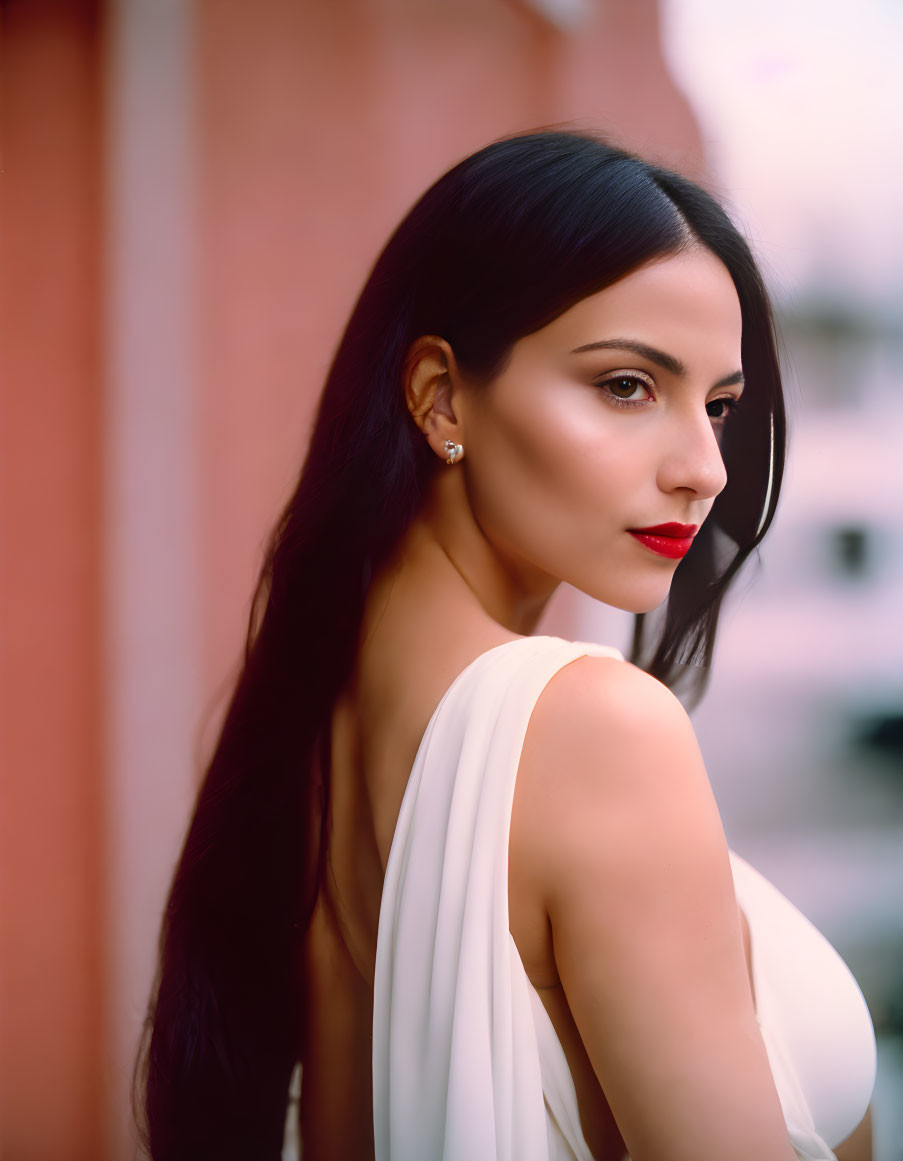 Dark-haired woman in white dress with red lipstick glances back.