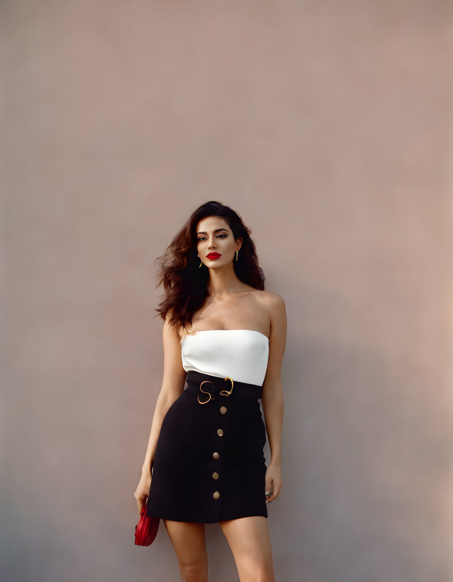 Fashionable woman in white strapless top and black skirt with gold buttons holding red clutch