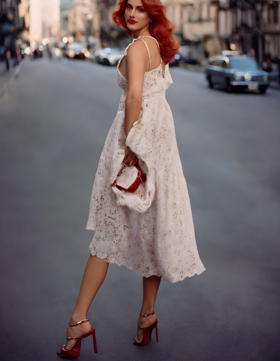 Red-haired woman in white lace dress and clutch on city street