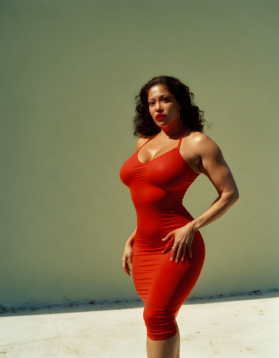 Confident woman in red dress with shadow on plain background