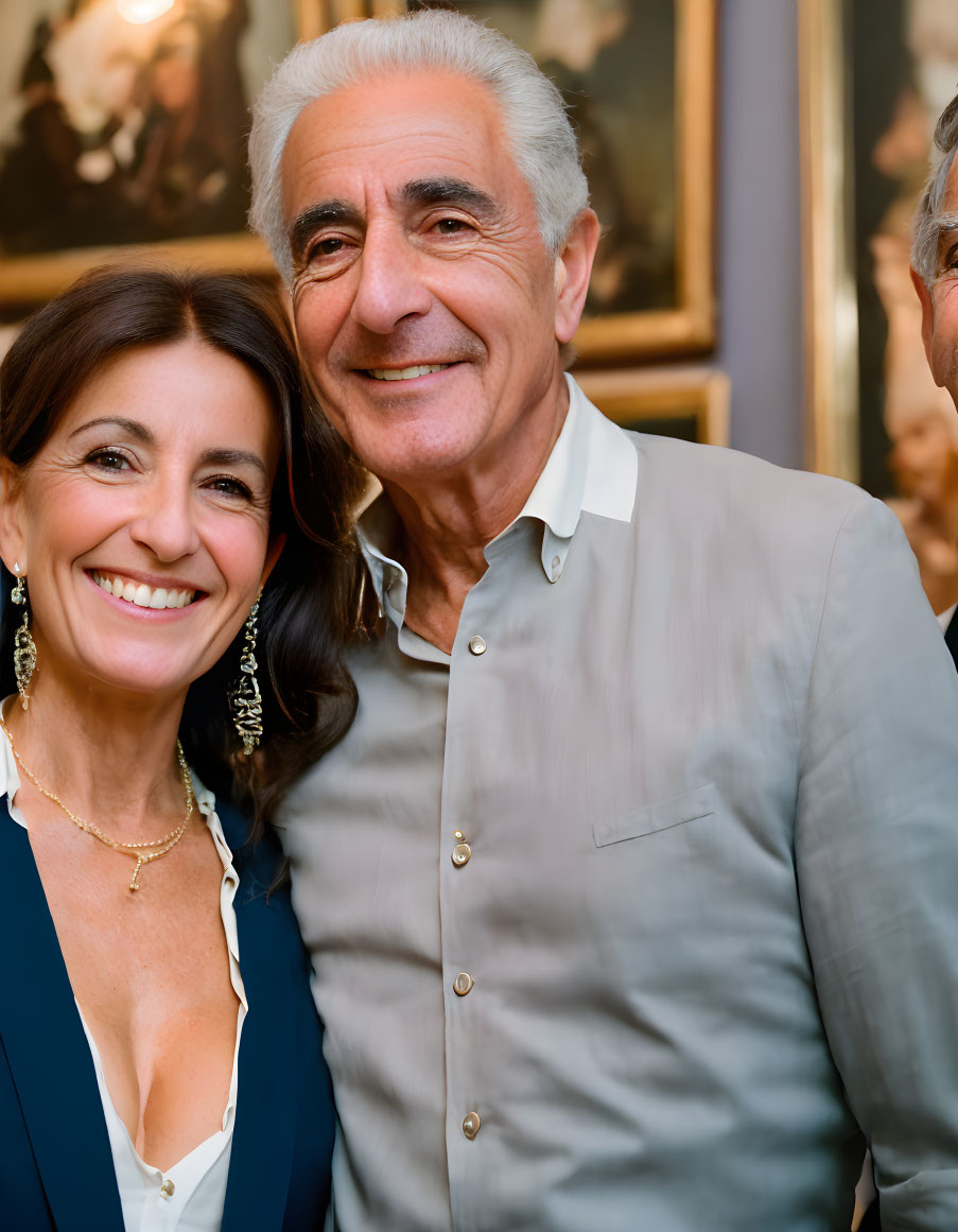 Smiling man and woman in gray and blue outfits with dark earrings