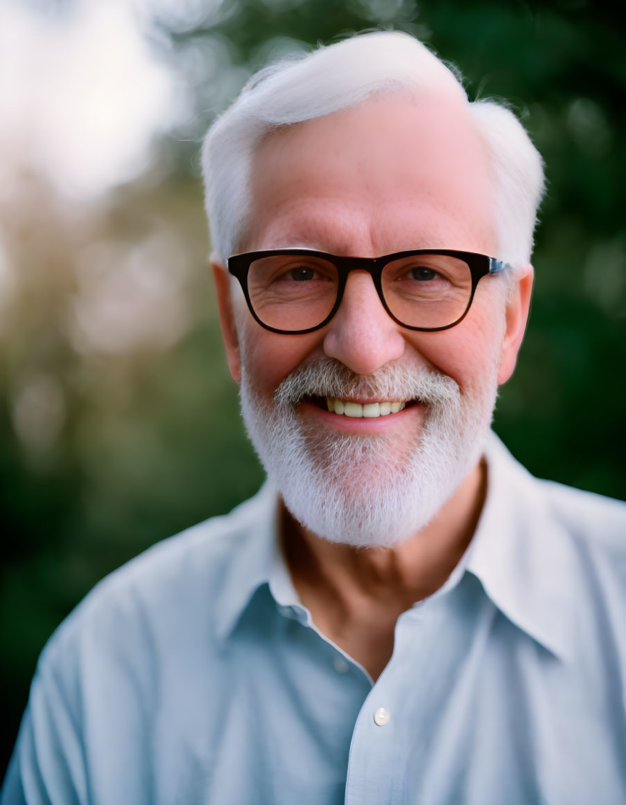 Elderly man with white beard and glasses in light blue shirt