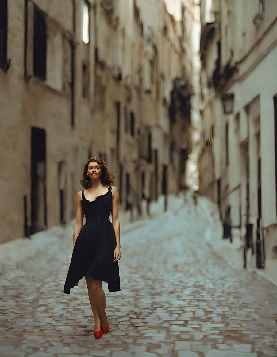 Woman in black dress and red heels in narrow cobblestone alley surrounded by old buildings