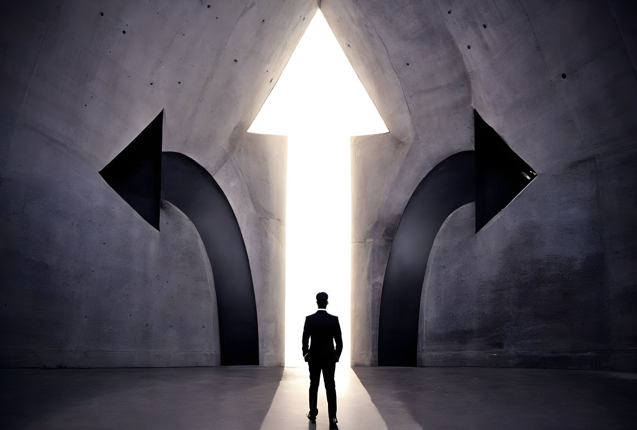 Silhouette of person in front of large triangular opening with light pouring in