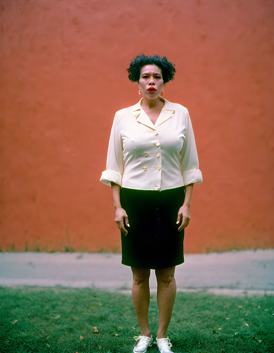 Woman in white blouse and black skirt against orange wall