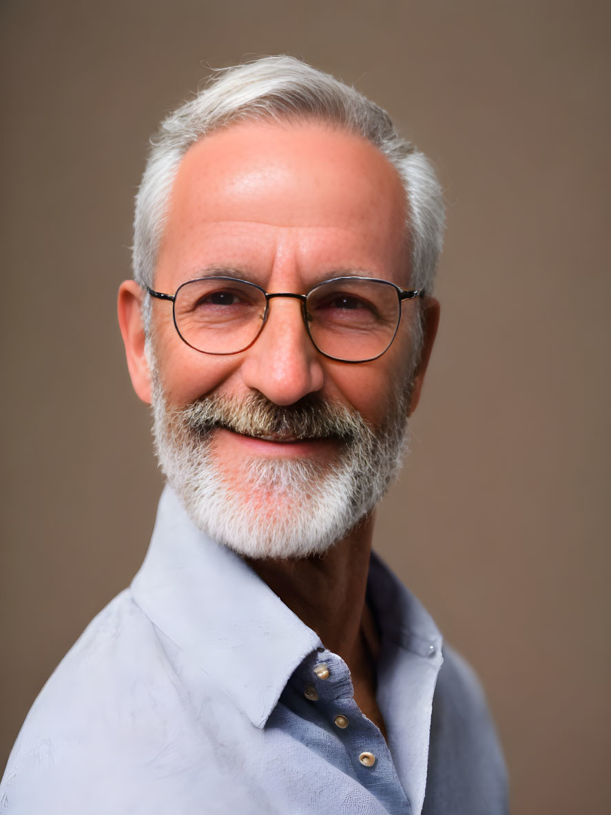 Elderly man with silver beard and glasses in light blue shirt