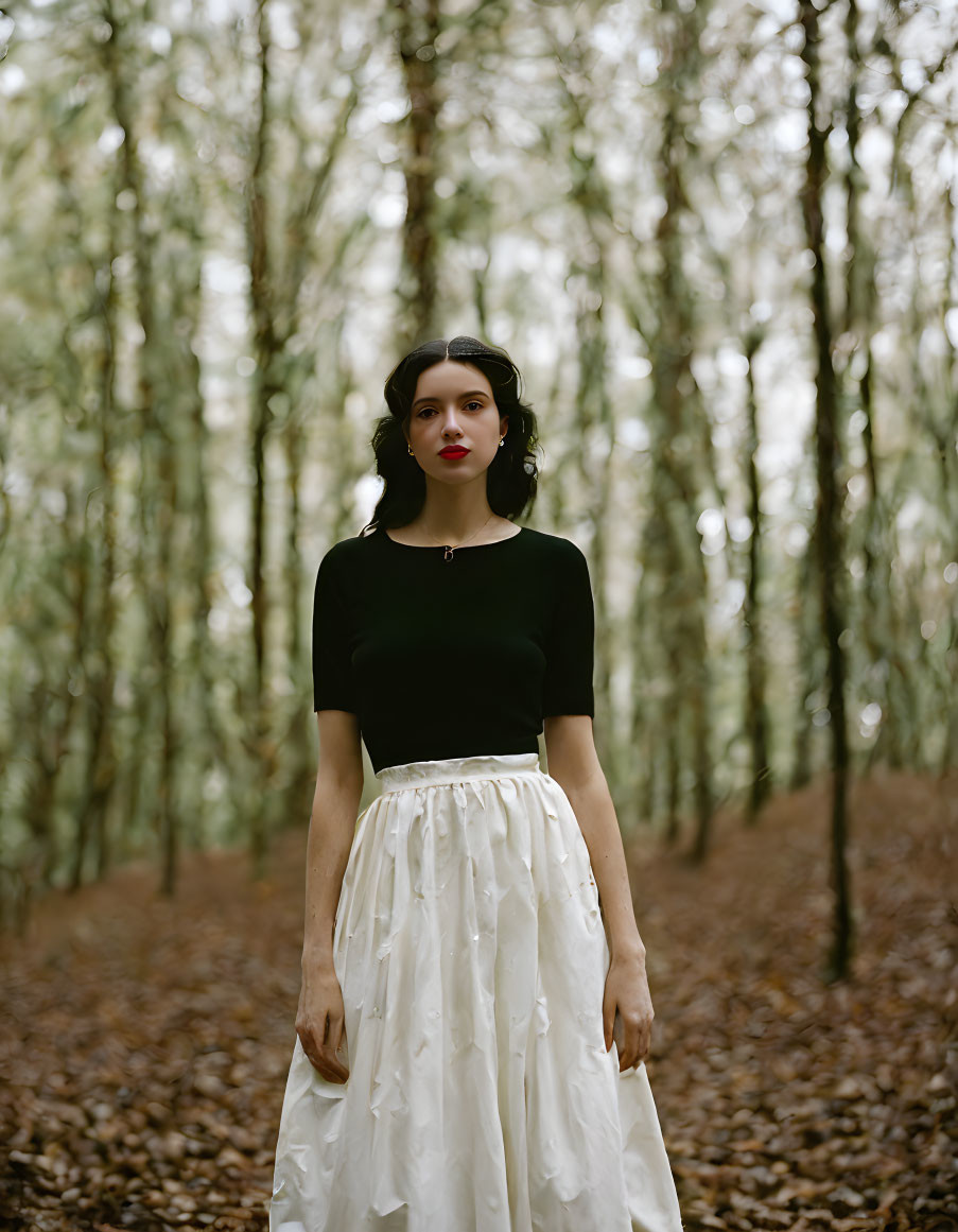 Woman in Black Top and White Skirt Standing in Forest among Tall Trees