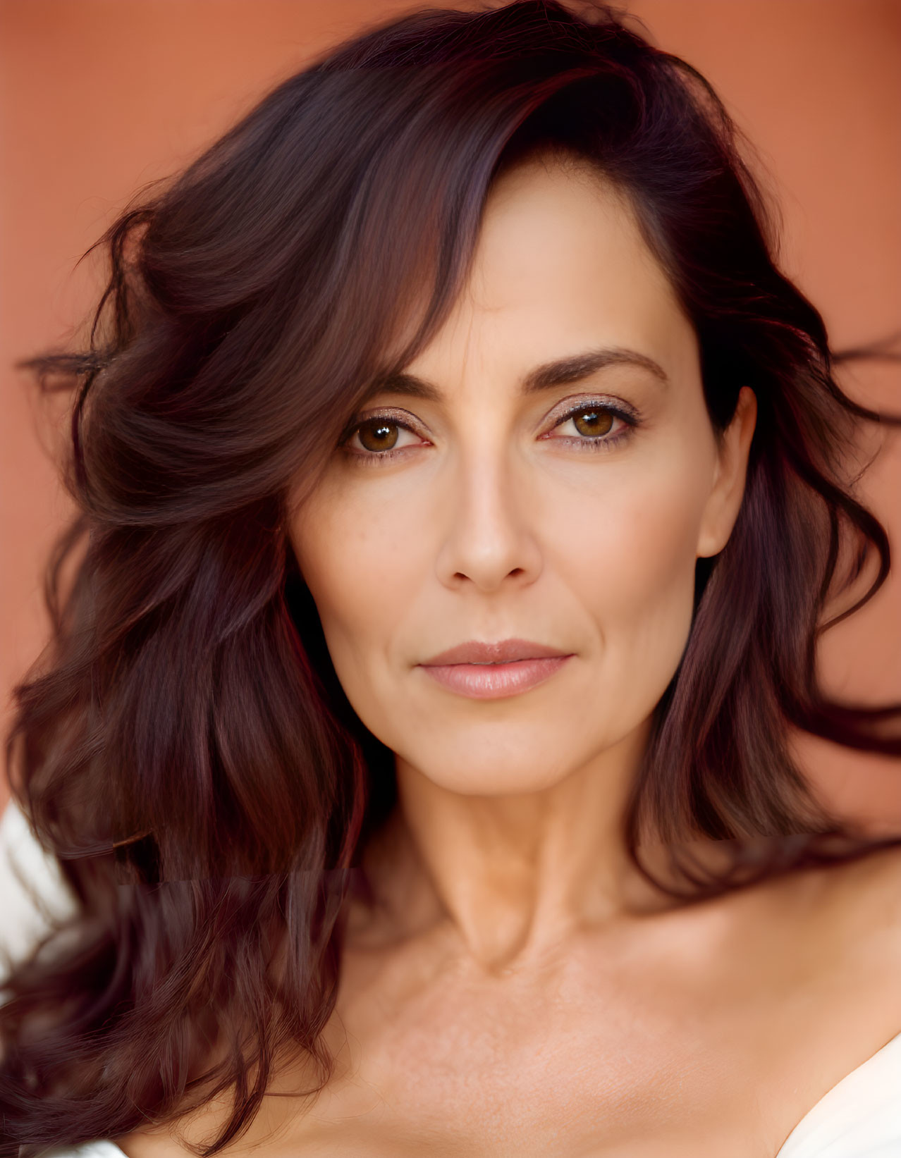 Woman with Shoulder-Length Brown Hair and Neutral Expression on Warm Background