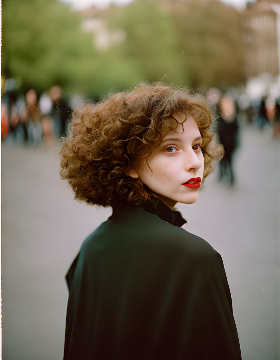 Curly-Haired Woman with Red Lipstick in Outdoor Setting