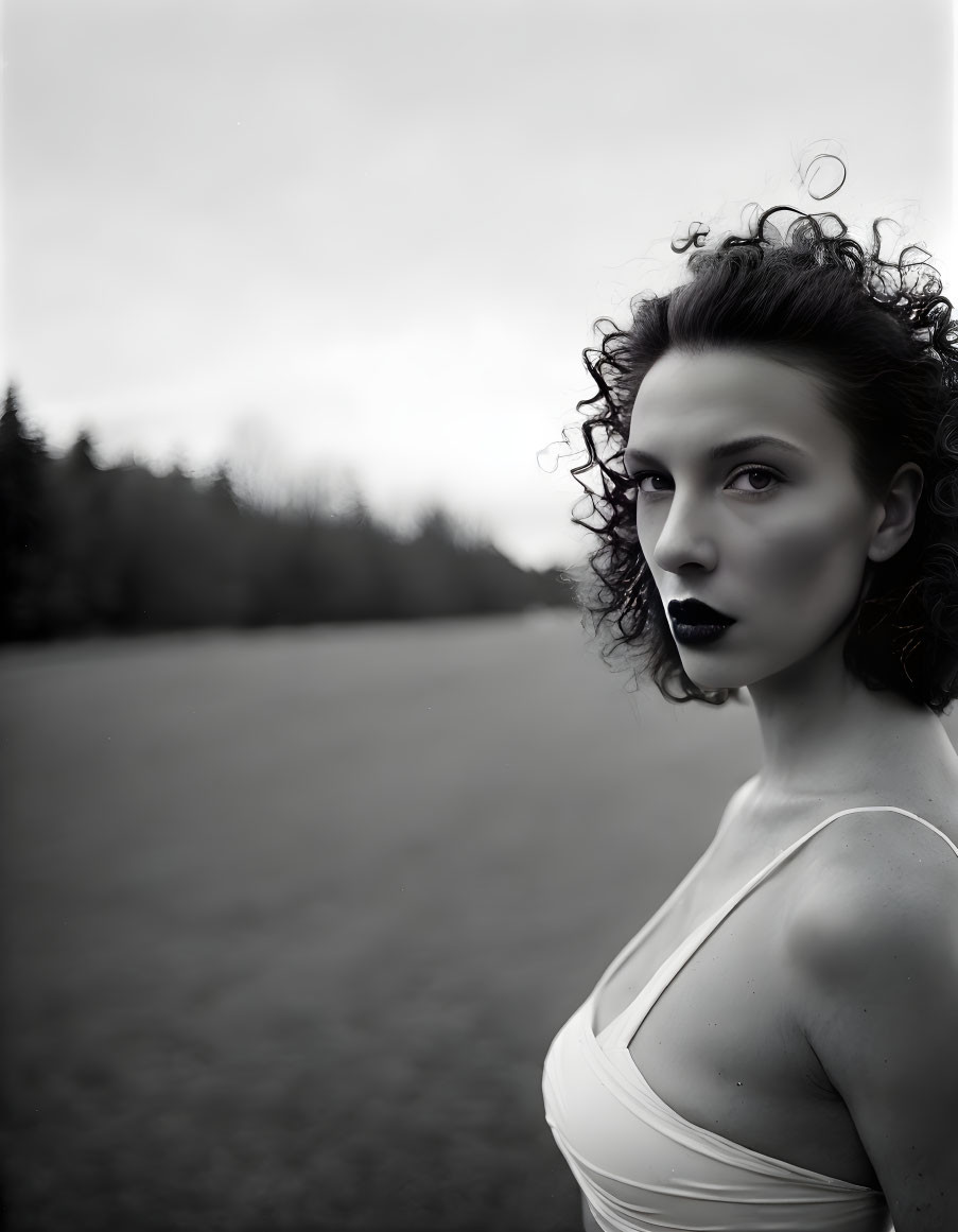 Curly Haired Woman in White Top in Moody Landscape