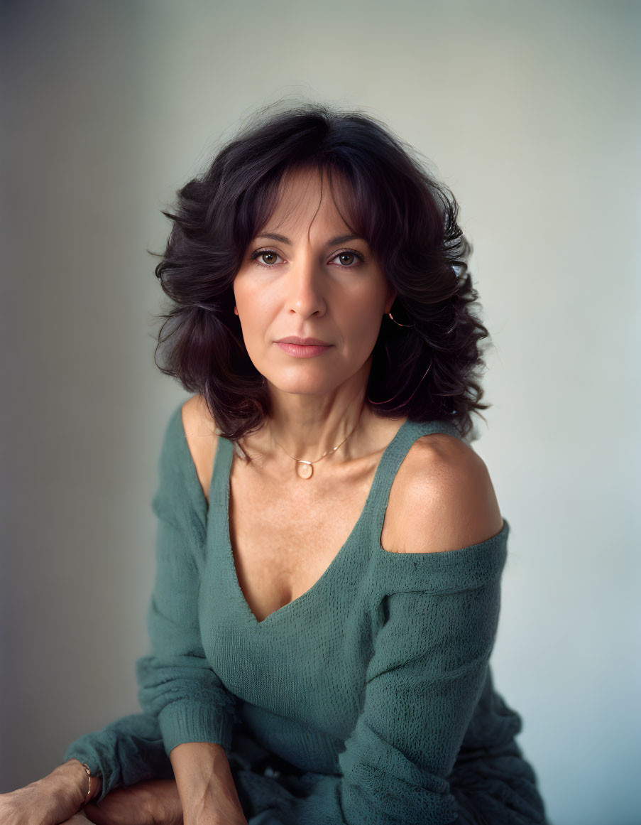 Portrait of woman with shoulder-length wavy brown hair in green sweater.