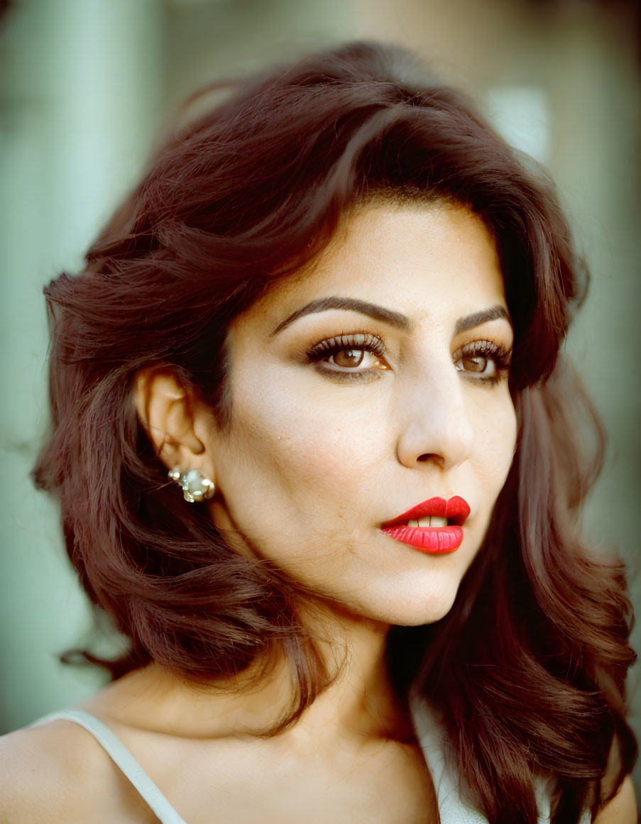 Portrait of woman with red lipstick and dark hair, gazing at camera.