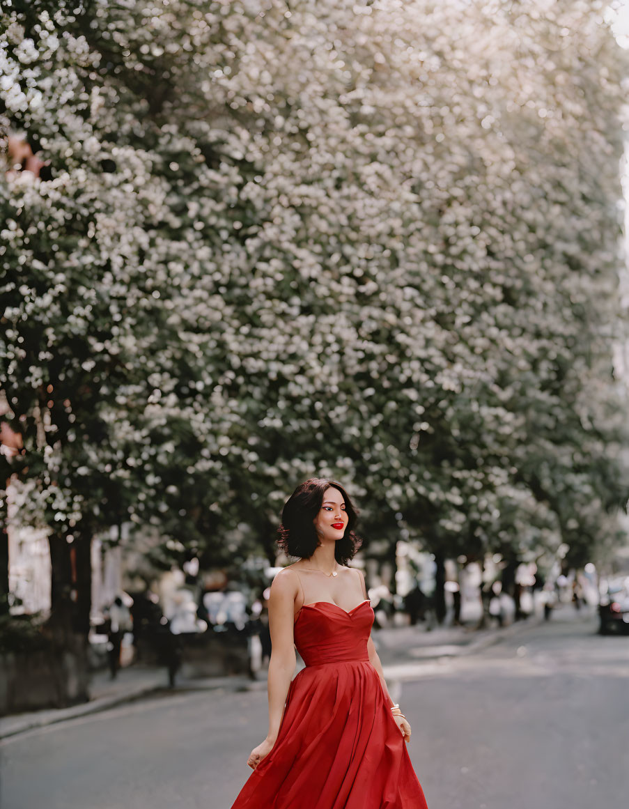 Woman in Red Dress Smiling on Blossoming Tree-Lined Street