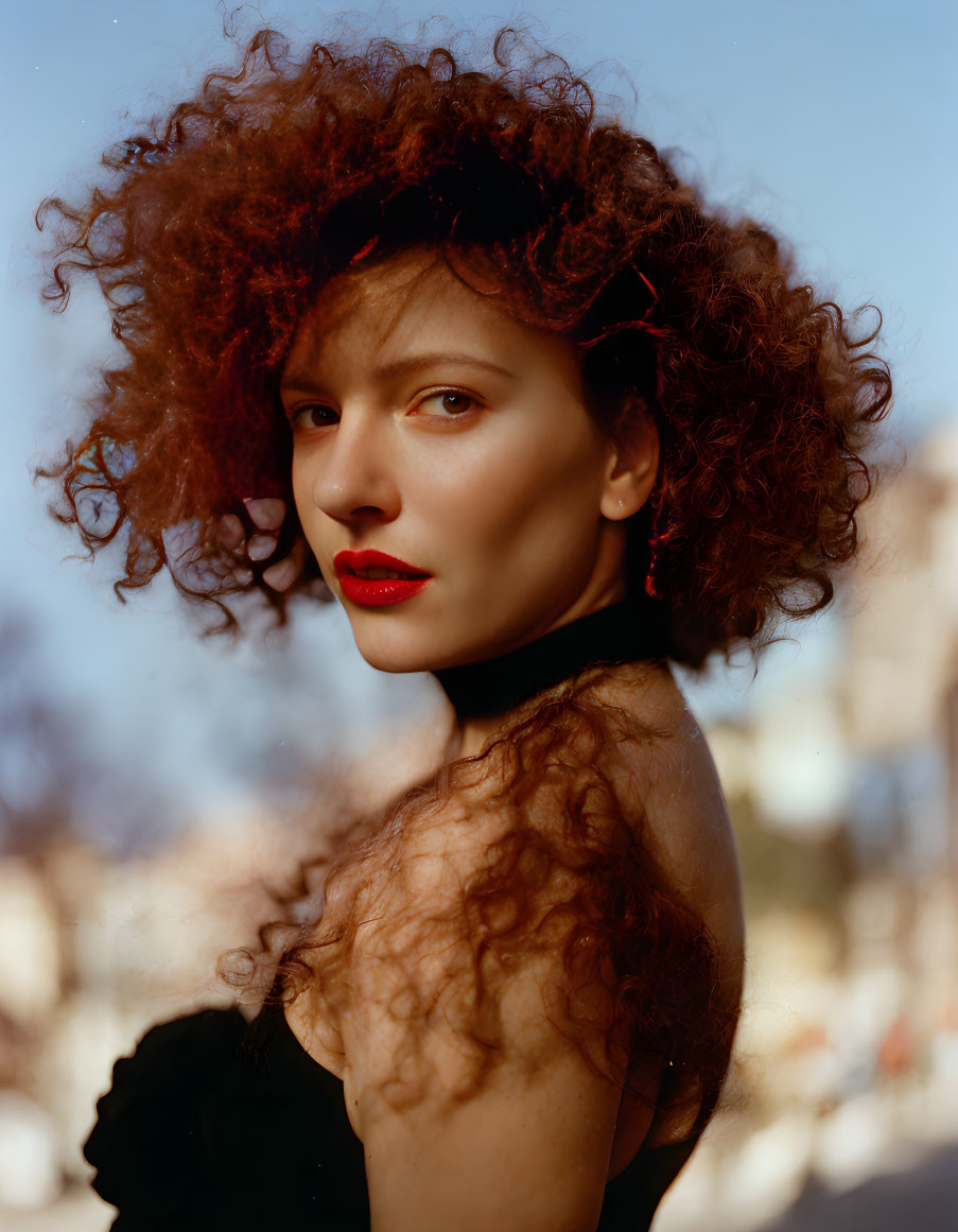 Curly Red-Haired Woman in Black Top with Red Lipstick gazes at Camera