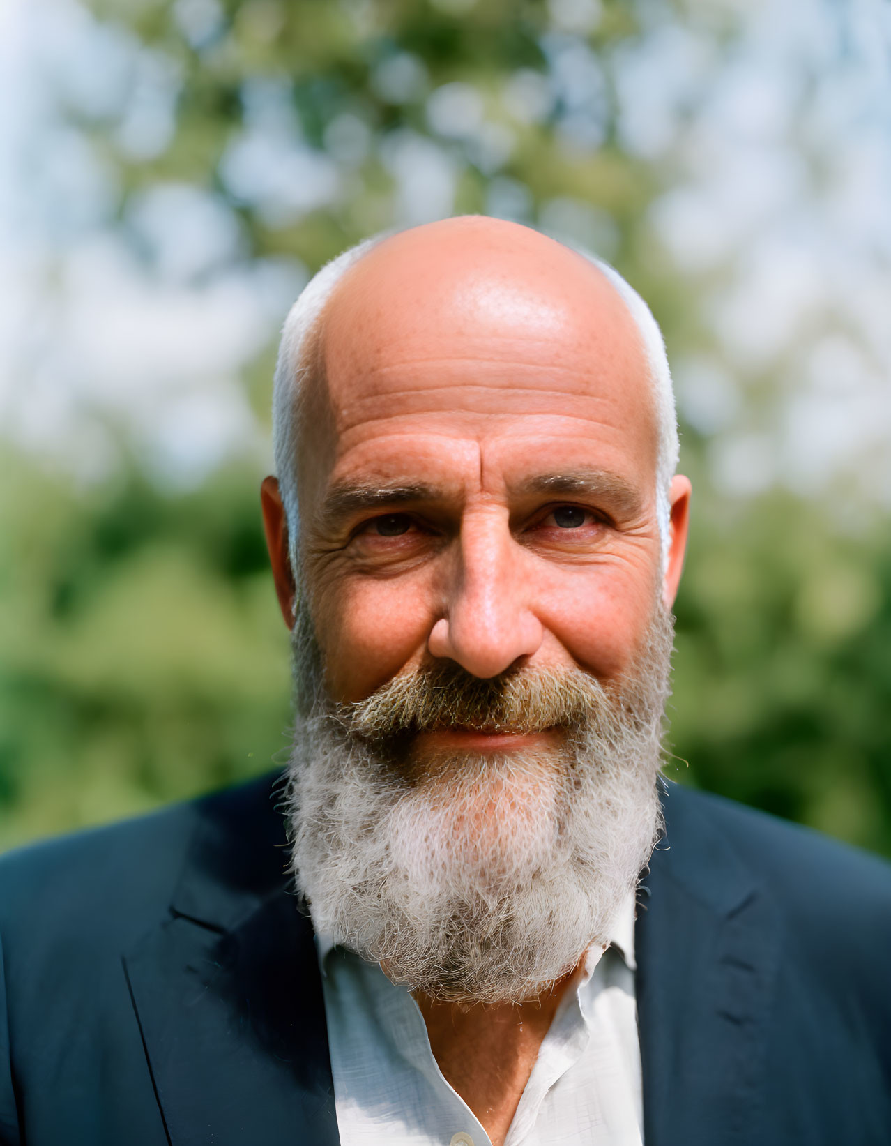 Bald Man with White Beard in Dark Suit on Green Background