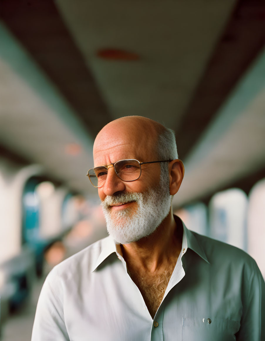 Elderly man with beard and glasses in softly lit setting