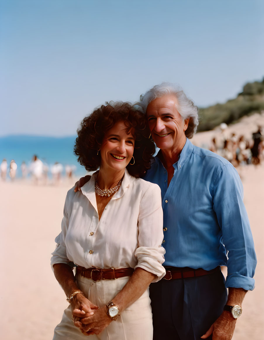 Elderly couple smiling on sunny beach with people in background