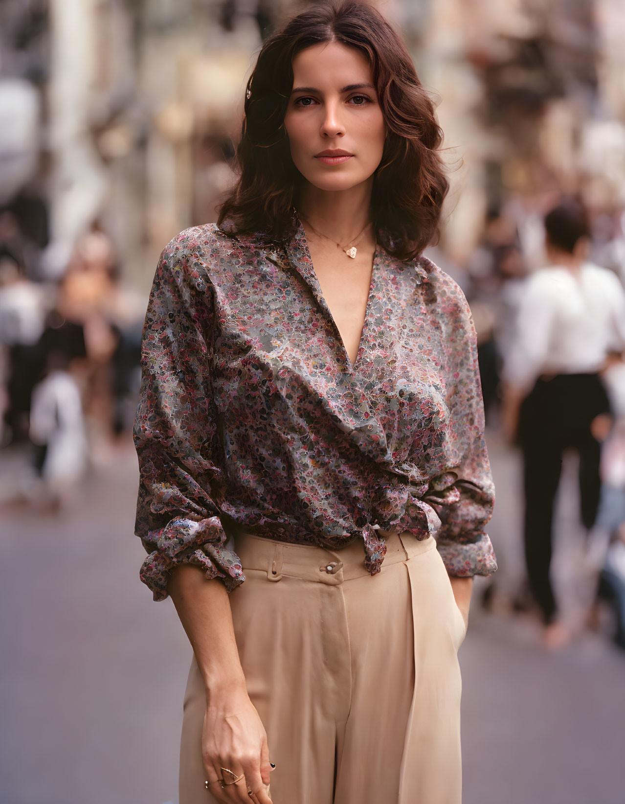 Woman with brown hair in floral blouse on city street