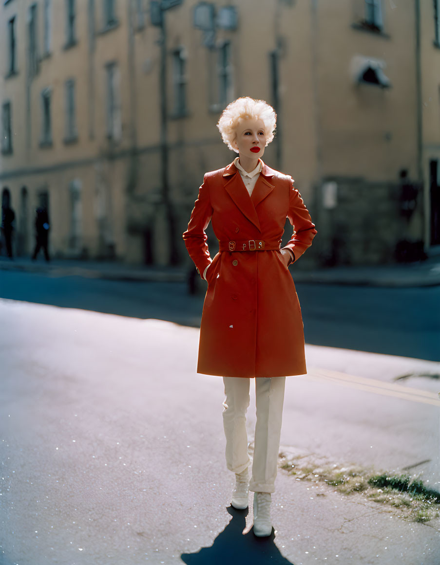 Platinum Blonde Person in Red Trench Coat on Sunny Street