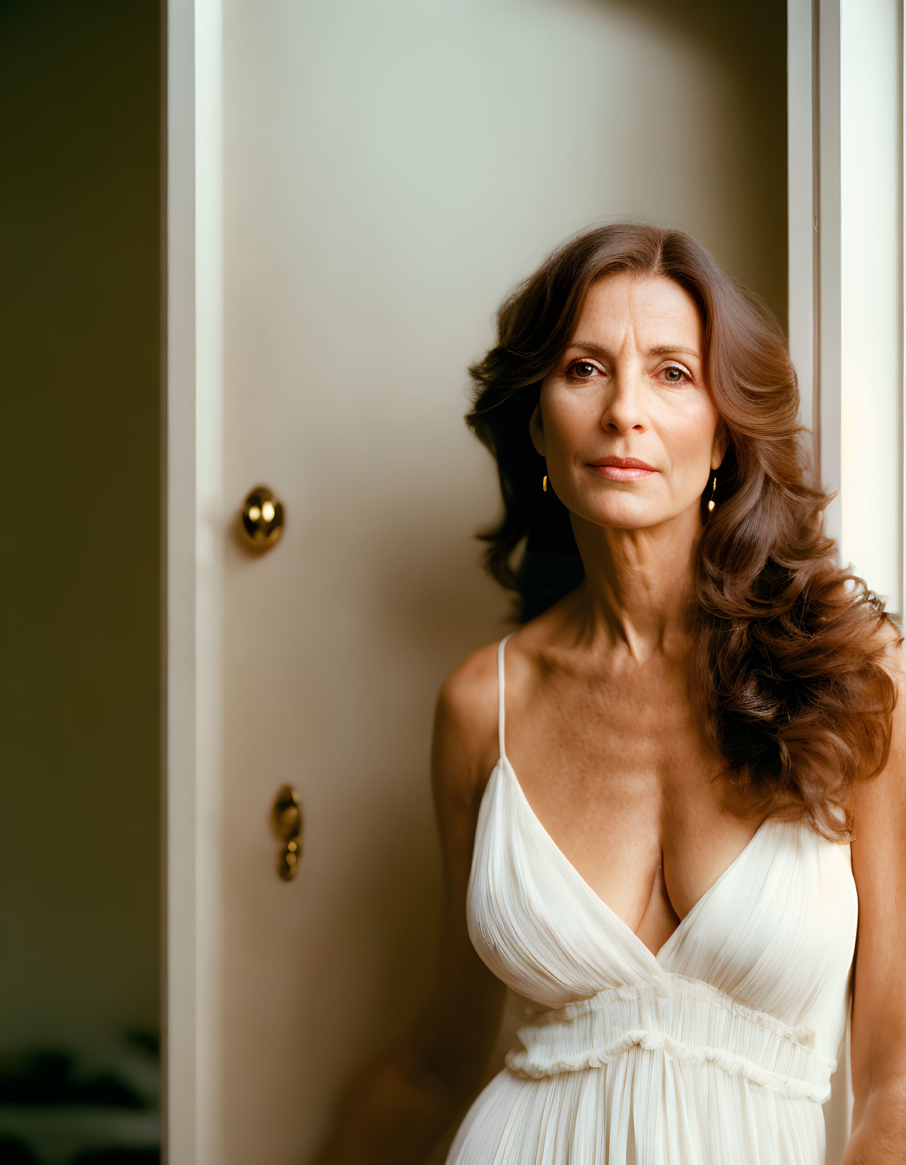 Serene woman in white dress by open door