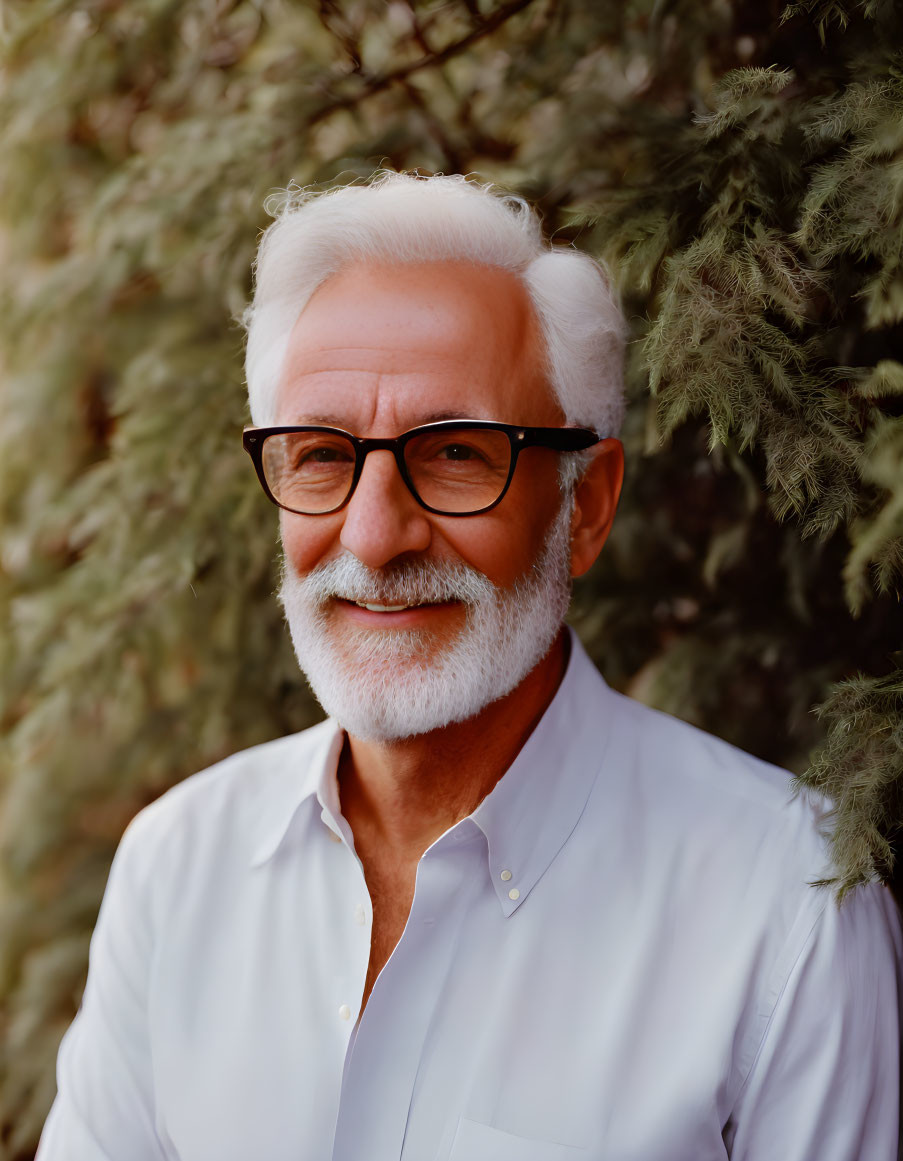 Elder gentleman with white hair and beard in glasses and white shirt against green background