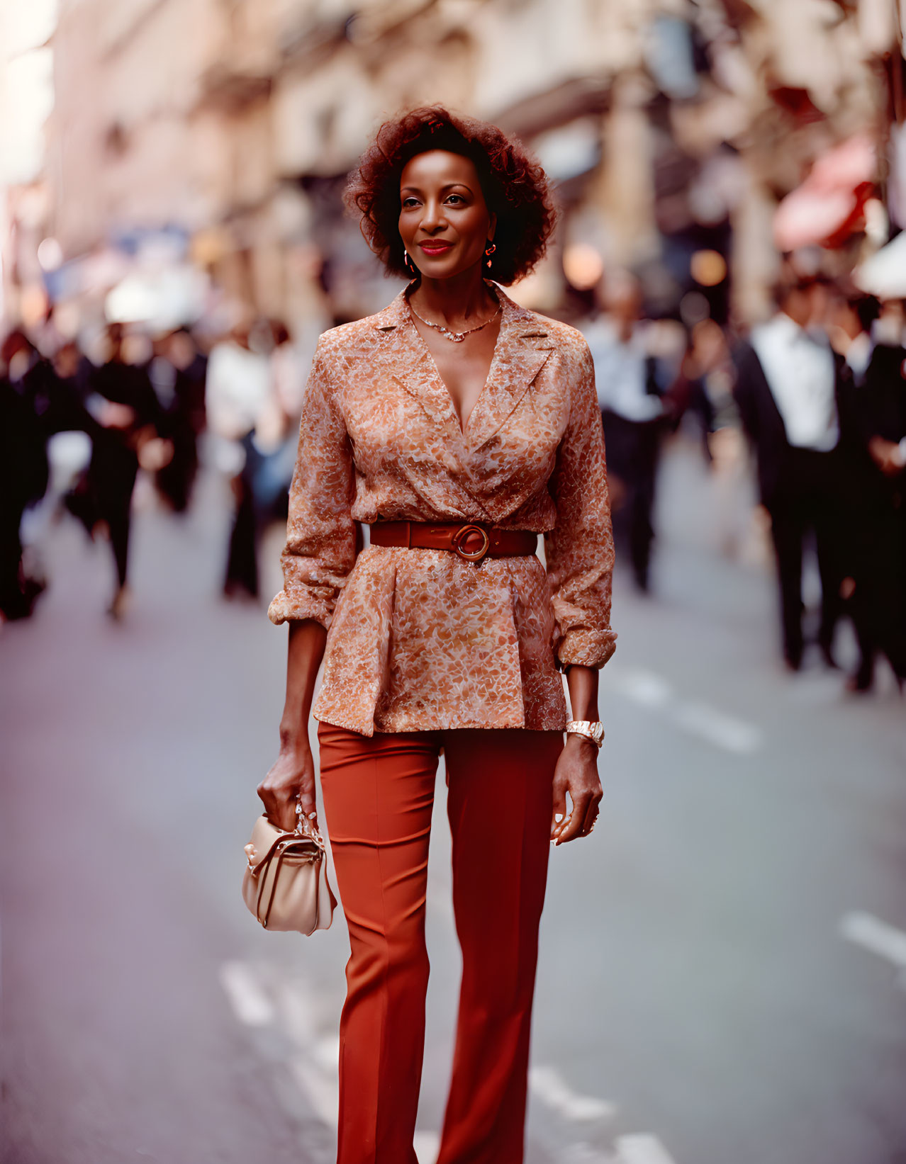 Fashionable woman in printed blouse and terracotta trousers on busy street