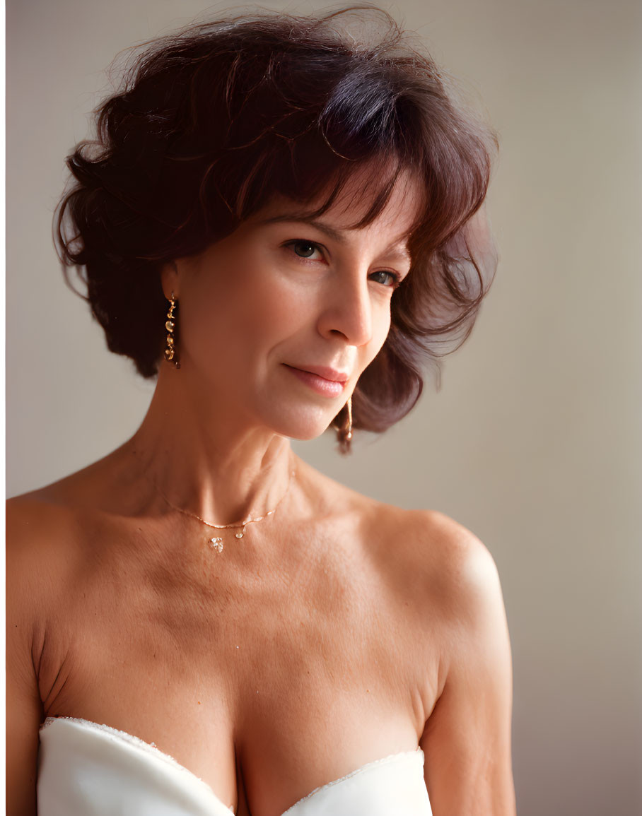 Smiling woman with brown hair in white dress and jewelry