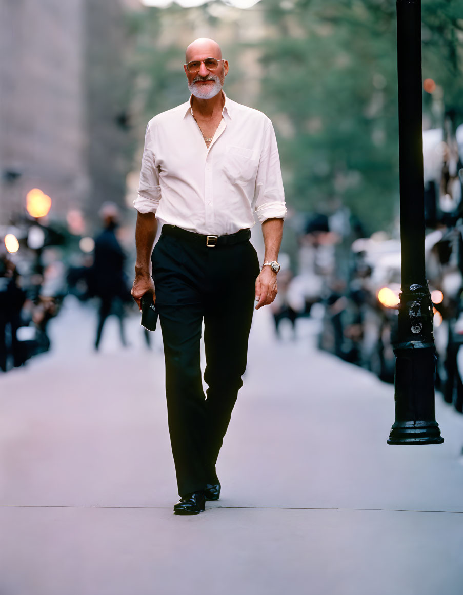 Bearded man in white shirt and black trousers walking in city street