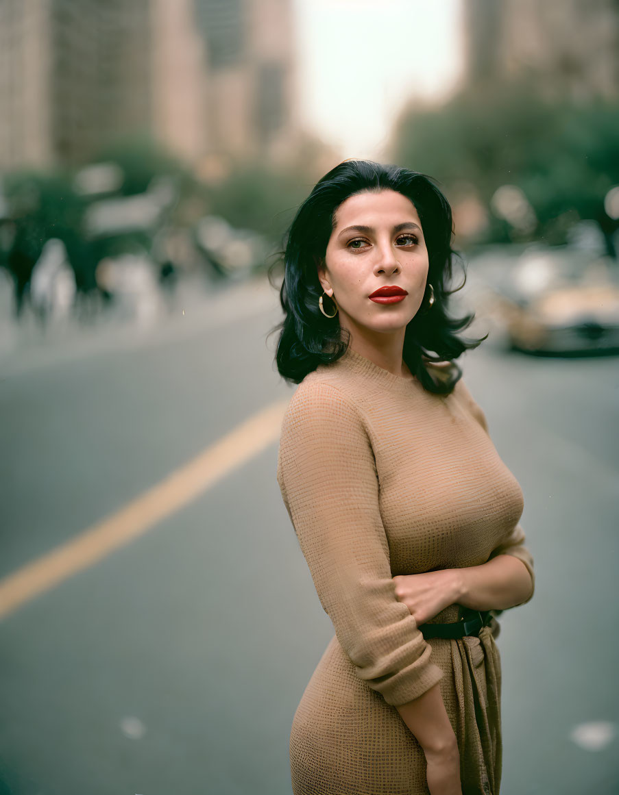 Confident Woman in Beige Dress Stands in Street Scene