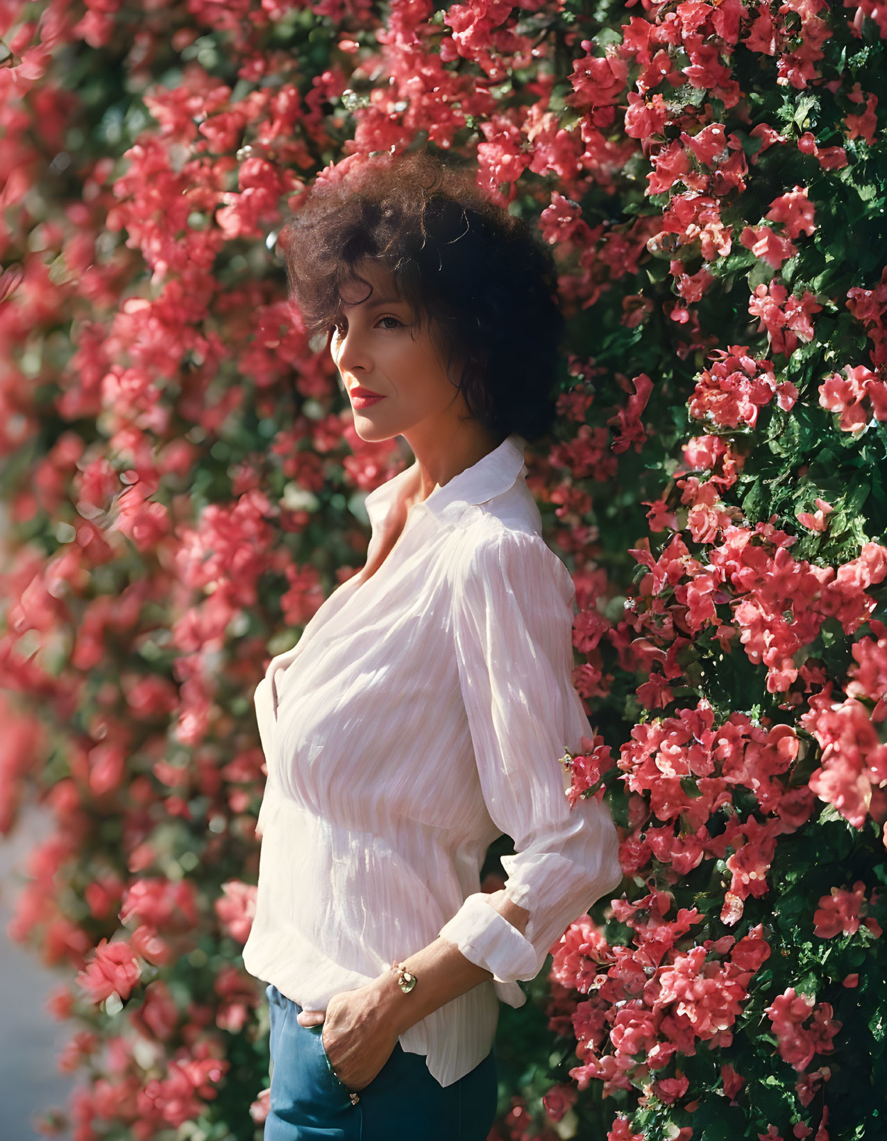 Curly-Haired Woman in White Blouse with Pink Bougainvillea Background