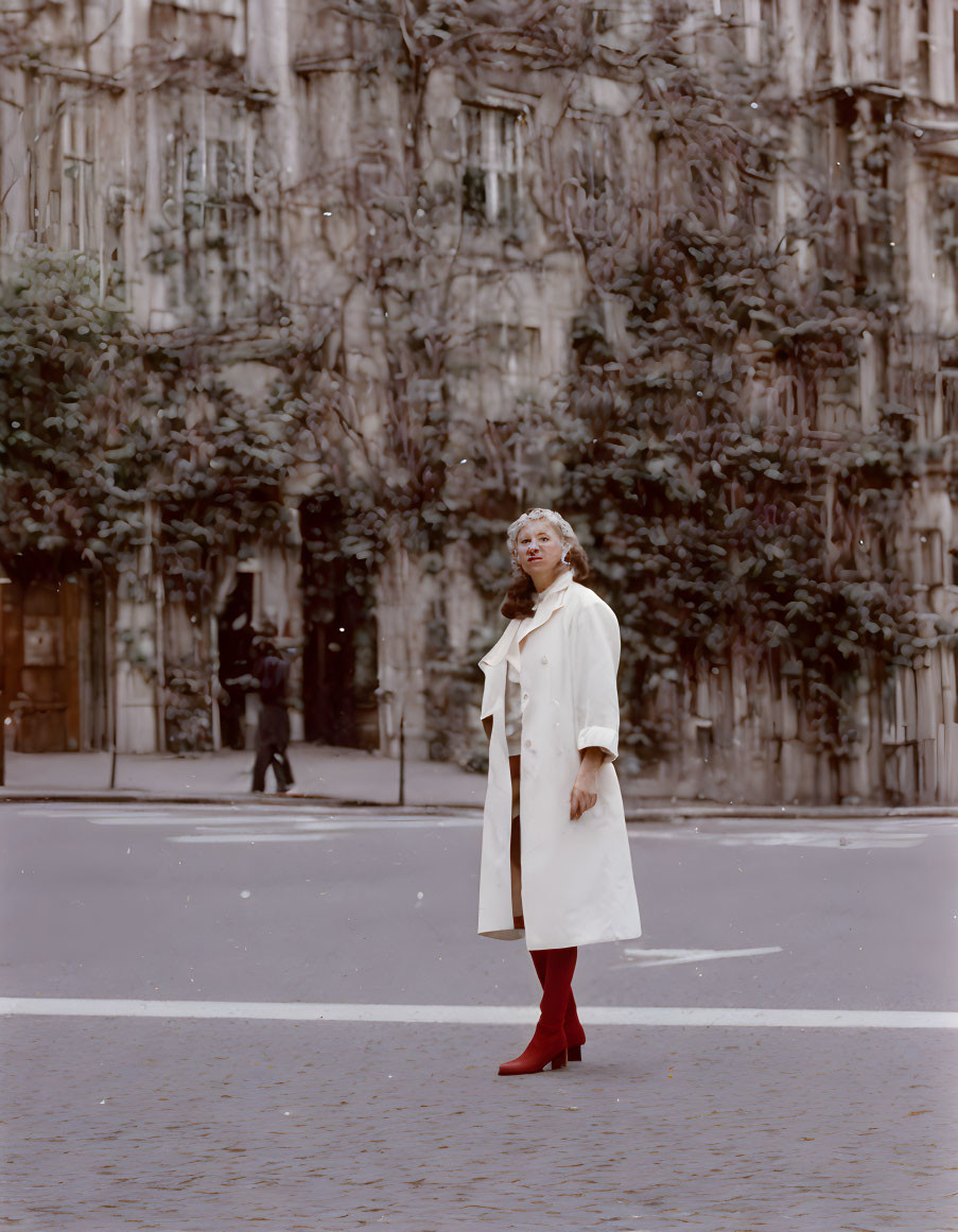 Person in white coat and red boots on urban street with blurred buildings