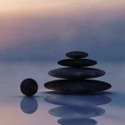 Seven Smooth Dark Stones Balanced on Reflective Surface Against Pink and Blue Background