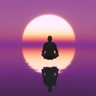 Silhouetted person meditating at sunset over tranquil water