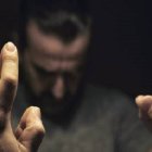 Blurred person with beard gesturing hands in dimly lit background