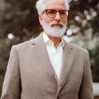 Elderly Man with White Beard and Glasses in Gray Blazer