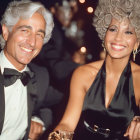 Elegant silver-haired couple in formal attire at event with onlooker