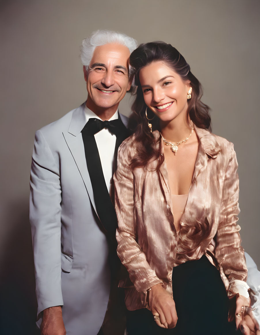 Smiling man in tuxedo and woman in satin blouse pose together