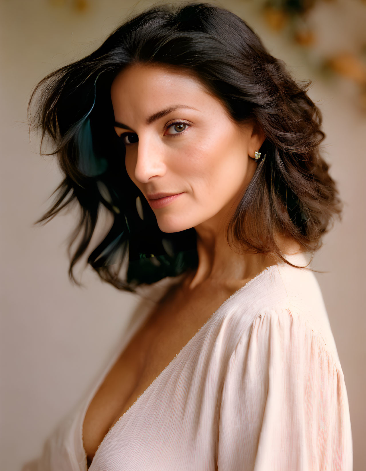 Dark-Haired Woman in Light Pink Blouse on Creamy Background