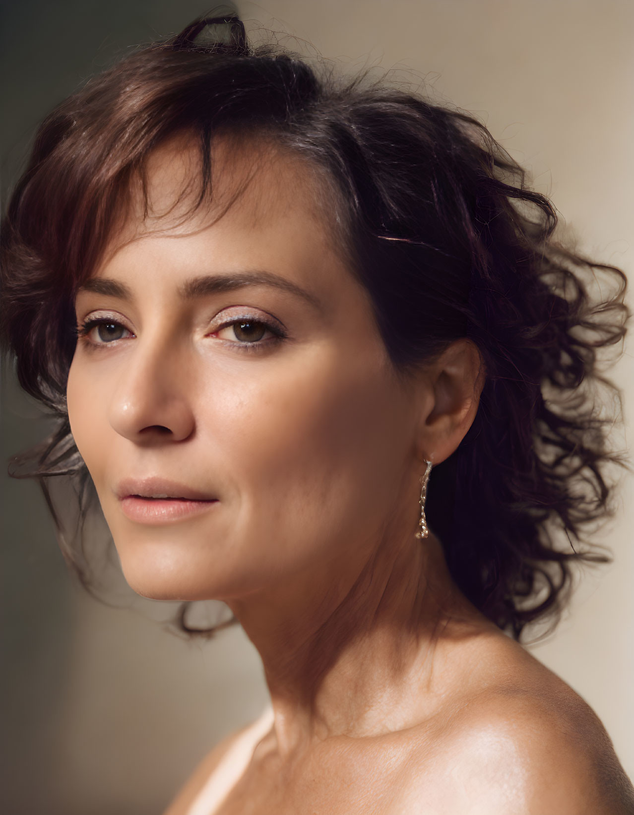 Portrait of woman with wavy dark hair and earring, looking away