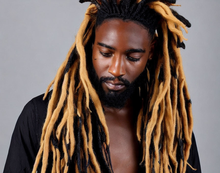 Man with Long Black and Blonde Dreadlocks in Black Shirt on Grey Background