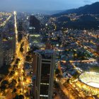 Cityscape at Night: Illuminated Buildings, Streets, and Roundabout with Mountain Backdrop