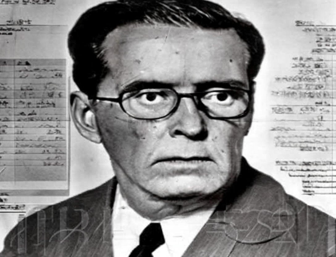 Middle-aged man in suit and tie with glasses, surrounded by typewritten documents