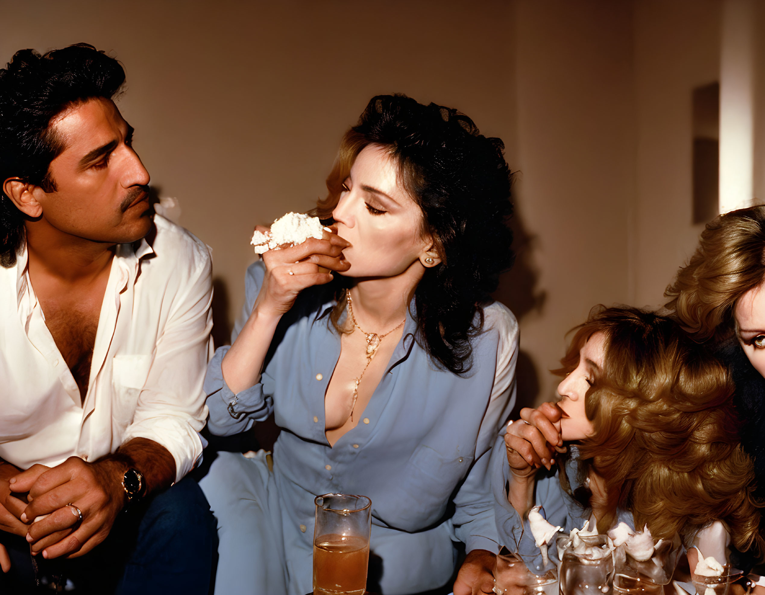 Man watching woman in blue shirt eating whipped cream with another woman observing