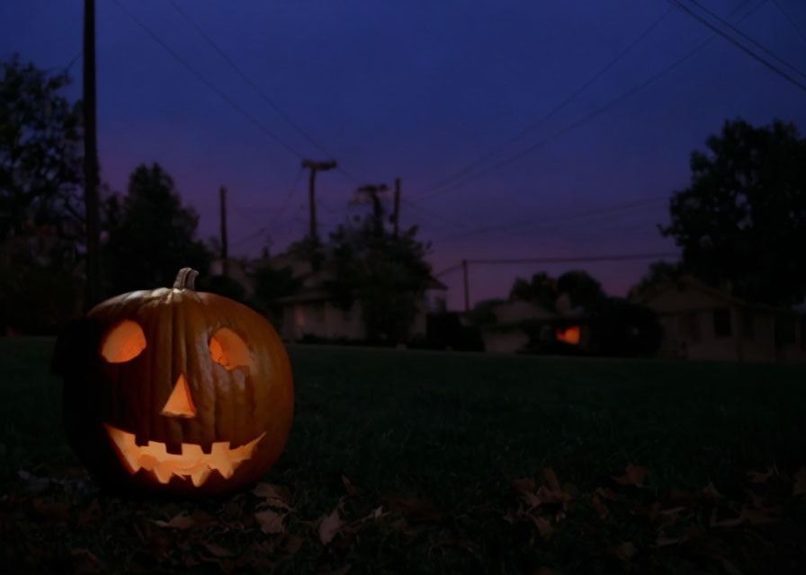 Twilight scene with jack-o'-lantern, houses, and scattered leaves