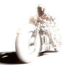 Bright high-key photo: biker in gear on chrome motorcycle with dramatic lighting