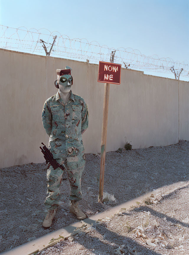 Mannequin in military uniform with skull face and rifle next to "NO ME" sign