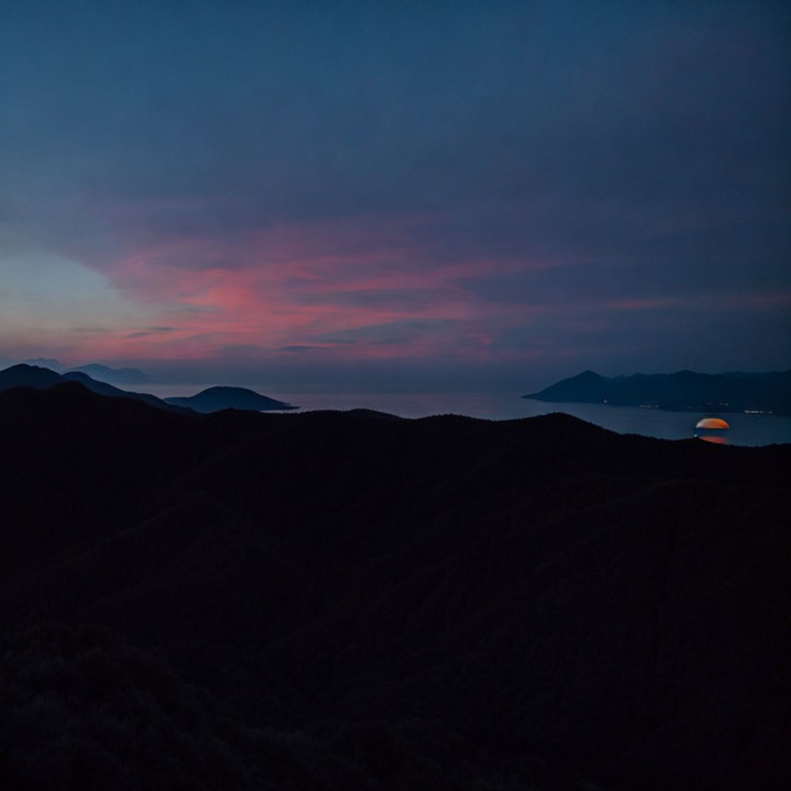 Twilight landscape: rolling hills, distant sea, and tranquil sky