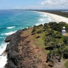 Aerial View of Rugged Coastline with Waves, Beach, and Lightning in Stormy Sky